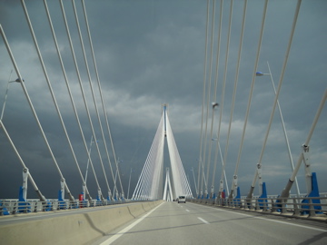 A car driving on the bridge under cloudy skies.