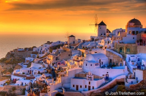 Sunset over Santorini's white buildings and sea.