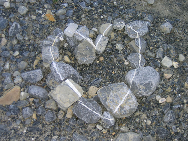 Heart shape made of stones on ground.