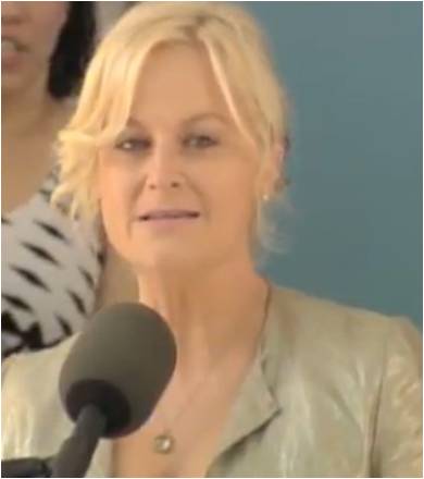 Woman speaking at a podium, light hair.