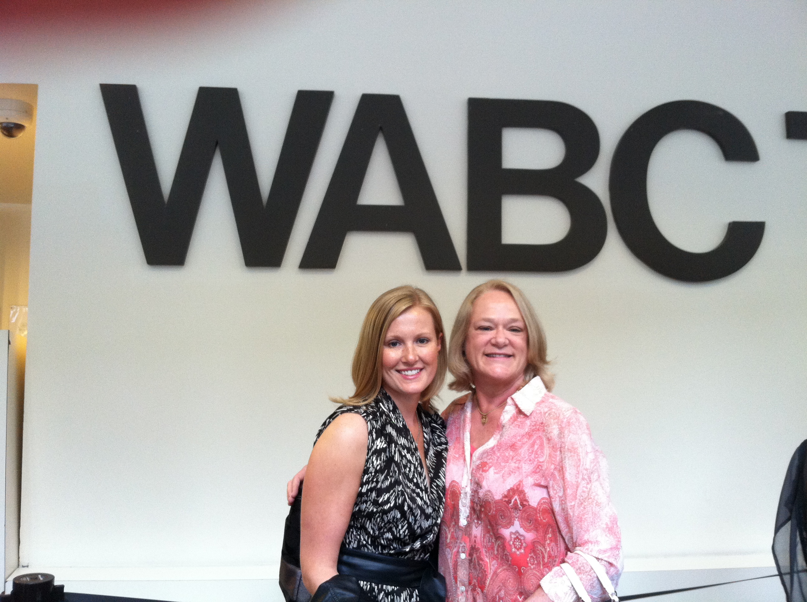 Two women standing in front of a wabc sign.