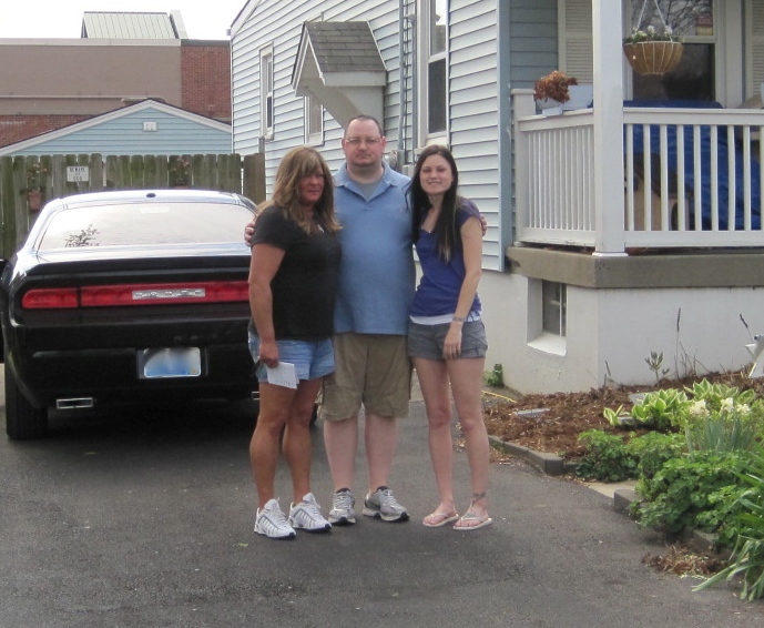 A man and two women standing in front of a car.
